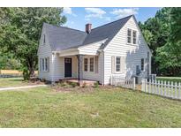 Charming white two-story home featuring a brick chimney, black shutters, and a manicured lawn at 2714 Wedgedale Ave, Durham, NC 27703