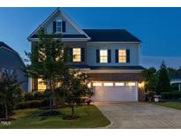 Charming two-story home featuring a brick and siding exterior, well-manicured lawn, and attached two-car garage at dusk at 437 Henmore Brook Dr Dr, Cary, NC 27519
