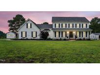 Charming white two-story home featuring black shutters, a covered porch and a lush green lawn at 4600 Smithfield Rd, Wendell, NC 27591
