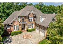 Striking two-story brick home with a circular driveway and manicured landscaping at 671 Bear Tree Crk, Chapel Hill, NC 27517
