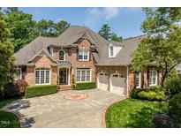 Traditional brick home featuring manicured landscaping, circular driveway, and attached two car garage at 671 Bear Tree Crk, Chapel Hill, NC 27517