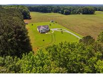 Aerial view of a beautiful country home on a large, green lawn, surrounded by trees and farmland at 6916 Morrow Mill Road, Chapel Hill, NC 27516