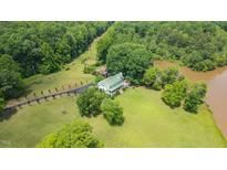 Stunning aerial view of a well-maintained home surrounded by lush greenery and a private pond at 771 Cedar Grove Church Rd, Roxboro, NC 27574