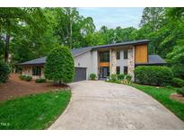 Stylish two-story home featuring stone and wood accents, lush landscaping and a curved driveway at 7816 Harbor Dr, Raleigh, NC 27615