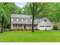 Charming two-story home with a welcoming front porch, attached garage, and lush green lawn at 8505 Stonegate Dr, Raleigh, NC 27615