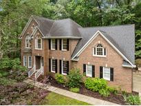 Traditional brick home with a well-manicured lawn and mature trees at 1004 Staffield Lane Ln, Chapel Hill, NC 27516
