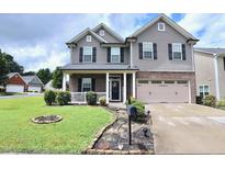 Charming two-story home with a well-manicured lawn, a covered porch and an attached two-car garage at 101 Claystone Dr, Gibsonville, NC 27249
