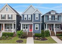 Charming blue two-story home featuring a welcoming front porch, red door, and well-maintained landscaping at 224 Daniel Ridge Rd, Wendell, NC 27591