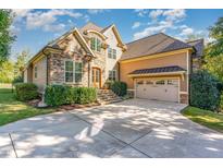 Stunning stone and tan home featuring a two-car garage, manicured lawn, and steps leading to the front door at 268 The Preserve Trl, Chapel Hill, NC 27517