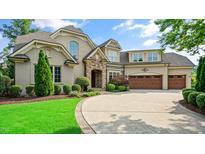 Stunning brick home featuring a stone entryway, manicured landscaping, and a spacious driveway leading to a three-car garage at 603 Hawks Ridge Ct, Apex, NC 27539