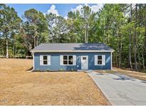 Charming blue one-story home featuring white trim and shutters, nestled in a wooded area at 679 Jasmine Rd, Fuquay Varina, NC 27526