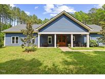 Charming blue home featuring a well-manicured lawn and a welcoming front porch with a striking wood front door at 741 Sinai Cir, Hillsborough, NC 27278
