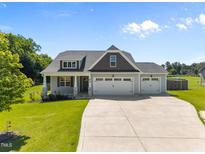 Charming home featuring a three-car garage, well-manicured lawn, and beautiful architectural details at 834 Mamie Upchurch Rd, Lillington, NC 27546