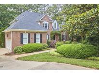 Beautiful brick home with lush landscaping, mature trees, and an attached garage at 8605 Stanton Pl, Raleigh, NC 27615