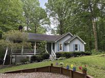 Charming home with landscaped front yard, covered porch, and light blue siding surrounded by lush trees at 8812 Valley Hill Ct, Apex, NC 27539
