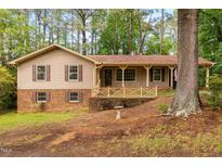 Charming two-story home with tan siding, brown shutters, brick accents, and a cozy front porch at 103 Tiara Ct, Garner, NC 27529