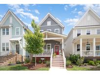 Charming two-story home showcasing a red door, inviting front porch and well-maintained lawn and landscaping at 1515 Millrock Trl, Wendell, NC 27591