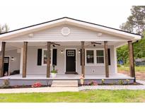 Charming home with a covered front porch featuring wooden pillars, ceiling fans, and freshly planted flowers at 3030 Forrester St, Durham, NC 27704