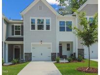 Charming townhome featuring a one-car garage, stone accents, and manicured front lawn at 381 Thompson Overlook Way, Smithfield, NC 27577