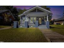 Charming gray home featuring a covered front porch, lovely landscaping, and classic architectural details at 507 S Mebane St, Burlington, NC 27215