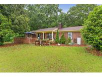 A beautiful backyard with a wooden deck, green grass, mature trees, and a brick home is perfect for relaxation at 5932 Johnson Pond Rd, Fuquay Varina, NC 27526