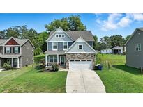 Charming two-story home with stone accents, a well-manicured lawn, and an attached two-car garage at 635 Black Angus Dr, Haw River, NC 27258