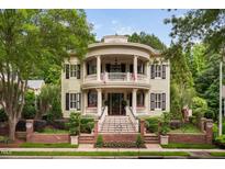 Stately two-story home featuring a double veranda, brick fence, beautiful landscaping, and black shutters at 8308 Society Pl, Raleigh, NC 27615