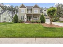 Charming two-story home with a well-manicured lawn, landscaped bushes, and a welcoming front porch at 925 Hidden Jewel Ln, Wake Forest, NC 27587