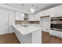 Bright kitchen features white cabinets, stainless steel appliances, and pendant lighting at 10535 Pleasant Branch Dr # 101, Raleigh, NC 27614