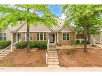 Inviting townhome featuring a mix of brick and stone accents, complemented by lush landscaping and a welcoming entrance at 11220 Avocet Ln # 104, Raleigh, NC 27617