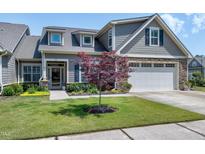 Charming home with a stone facade, manicured lawn, and an attached two car garage at 115 Thornwhistle Pl, Garner, NC 27529