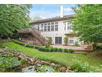 A home's beautifully landscaped backyard features a pond, patio, deck, and lush greenery at 12212 Ashton Woods Ln, Raleigh, NC 27614