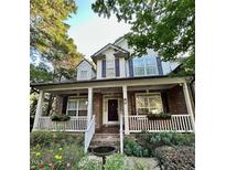 Charming two-story brick home featuring a welcoming front porch with white columns and lush landscaping at 12212 Ashton Woods Ln, Raleigh, NC 27614