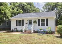 Charming single-story home with a light blue door, brick steps, and a cozy front yard seating area at 1408 Ida St, Durham, NC 27705