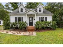 Charming Cape Cod home with dormer windows, black shutters, brick steps, and mature landscaping at 1541 Shadylawn Dr, Burlington, NC 27215