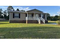 Charming single-story home featuring a cozy front porch and well-maintained lawn on a sunny day at 195 Washington Ln, Cameron, NC 28326