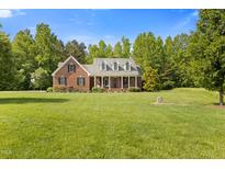 Charming brick home featuring a welcoming front porch and lush, green lawn at 200 Daniel Ridge Ln, Roxboro, NC 27574