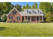 Charming brick home featuring a manicured lawn and inviting front porch with classic architectural details at 200 Daniel Ridge Ln, Roxboro, NC 27574