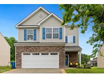 Charming two-story home featuring stone accents, blue shutters, and an attached two-car garage at 2004 Tennessee Rd, Durham, NC 27704
