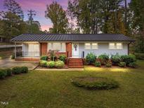 Charming single-story home featuring a brick facade, well-maintained landscaping, and a metal roof at 203 W Boundary St, Cary, NC 27513