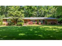 Charming brick home boasts a lush green lawn and mature trees, creating a welcoming curb appeal at 2053 Nottingham Ln, Burlington, NC 27215