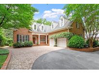 Charming brick home with dormers, lush landscaping, and a brick driveway leading to a three-car garage at 3509 Carlton Square Pl, Raleigh, NC 27612