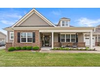 Charming home with a brick facade, covered porch, manicured lawn, and neatly trimmed shrubs at 4612 Hanging Fern Ln, Raleigh, NC 27604