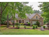 Charming brick home features a manicured lawn and lush landscaping with a welcoming front porch at 504 Belmont Cir, Wake Forest, NC 27587