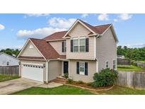 Charming two-story home featuring tan siding, brown roof, attached two car garage, and manicured landscaping at 5321 Longspur Dr, Snow Camp, NC 27349