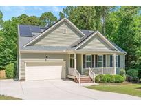 Charming home featuring a 2-car garage, solar panels and a welcoming front porch surrounded by a lush, landscaped lawn at 6512 Blalock Forest Dr, Willow Springs, NC 27592