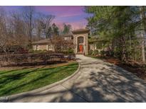 Beautiful brick home with well-manicured landscaping, long driveway, and red front door at 10210 Governors Drive Dr, Chapel Hill, NC 27517