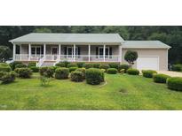 Charming ranch-style home featuring a metal roof, covered porch, and meticulously manicured front yard at 107 Oak Park Dr, Benson, NC 27504