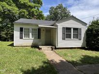 Traditional single-story home with classic siding and shutters, surrounded by mature trees and a green lawn at 1202 Kilby St, Burlington, NC 27215