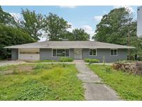 Charming single-story home with an attached garage, gray brick exterior, and large front yard in a quiet neighborhood at 1407 Arnette Ave, Durham, NC 27707